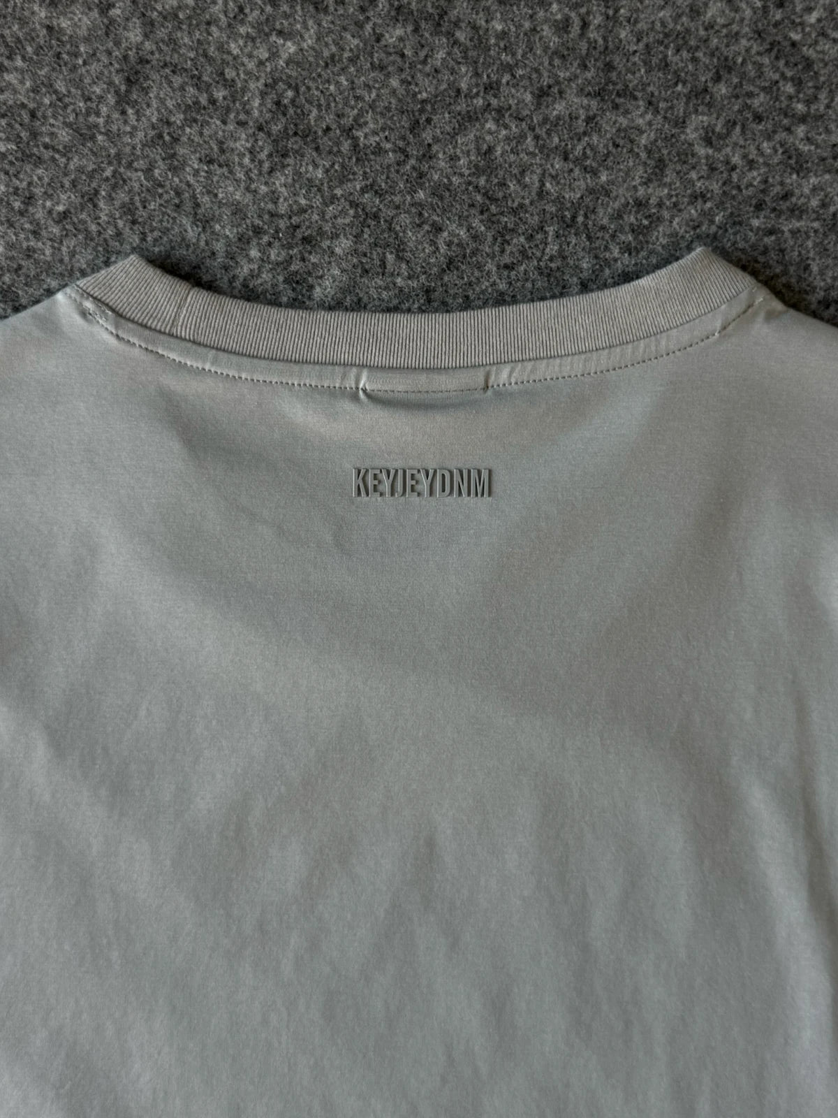 Dettaglio stampa posteriore KeyJey DNM su t-shirt in cotone grigio | Archivio Tessile