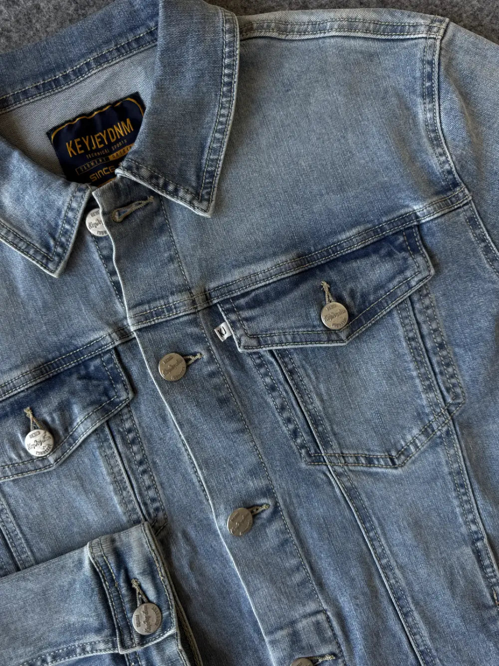 Dettaglio bottone logato e bottone polso giacca denim - Archivio Tessile