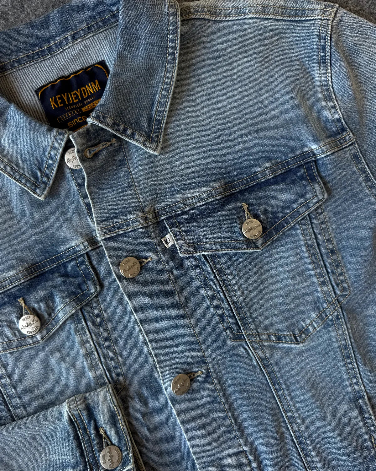 Dettaglio bottone logato e bottone polso giacca denim - Archivio Tessile